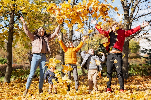 Familia joven feliz con tres hijos en el parque de otoño amor y ternura camina en la temporada