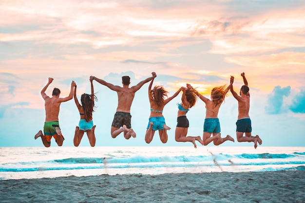 Felices Amigos Exitosos Saltando En La Playa Foto Premium 