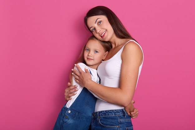 Feliz hermosa joven madre abrazando a su pequeña hija alegre atractiva