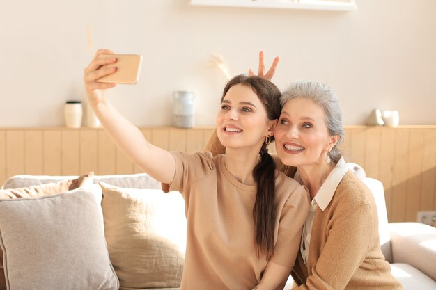 Feliz Madre E Hija De Mediana Edad Tomando Selfie En Casa Foto Premium