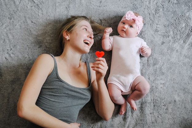 Feliz Madre E Hija Una Nina El Bebe El Recien Nacido La Mama Yace En La Cama De La Superficie Jugando Con Juguetes Sesion De Fotos 4 5 Meses Endecha Plana Vista Superior