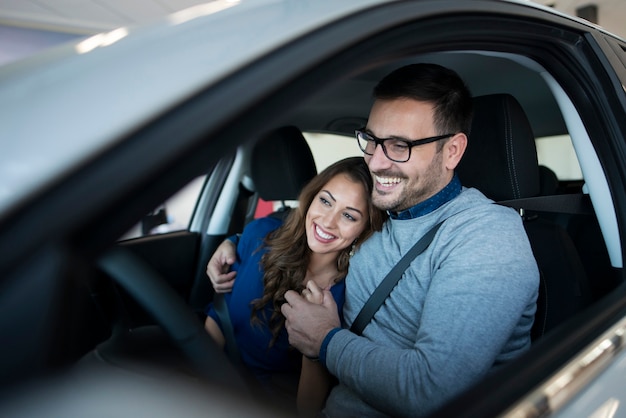 Feliz pareja joven disfrutando de su coche nuevo Foto gratis