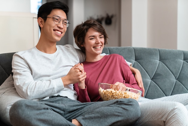 Feliz Pareja Multinacional Comiendo Palomitas De Maíz Y Viendo Una Película Mientras Está 