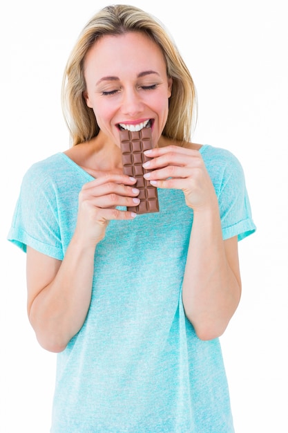 Feliz rubia comiendo barra de chocolate | Foto Premium