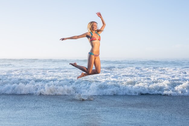 Feliz Rubia Saltando En La Playa En Bikini Foto Premium