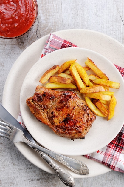 Filete De Cerdo Jugoso Y Dorado Sobre Hueso Con Patatas Fritas Foto