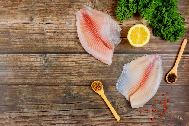 Filete de pescado crudo de tilapia en la mesa con limón y especias