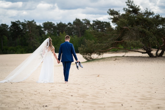 Foto de paisaje de una pareja caminando sobre la arena el día de su boda Foto gratis