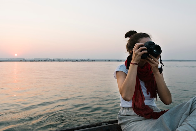 Fotógrafo de sexo femenino que se sienta en un barco en el río ganges Foto gratis