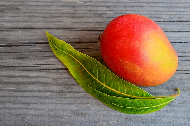 Fruto de mango fresco y hojas de árbol de mango en madera Foto Premium 