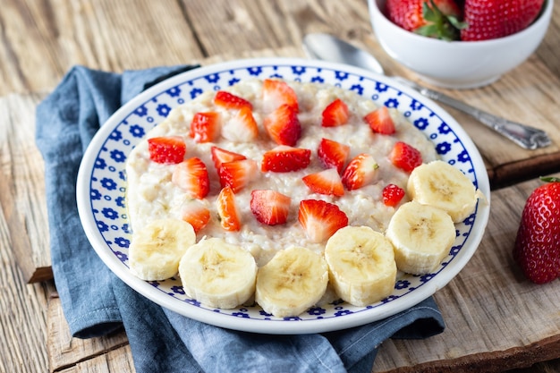 Gachas de avena con fresas y plátano sobre mesa rústica de madera