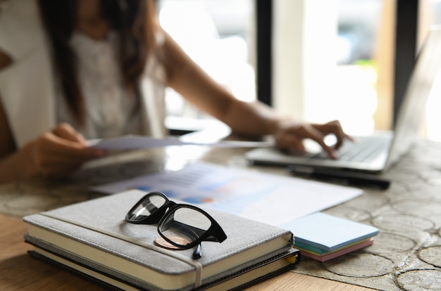 Gafas colocadas en cuadernos personas borrosas de fondo están sentados