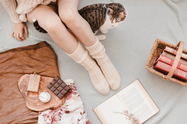 Gato caminando cerca de la mujer y libros sobre la cama | Foto Gratis