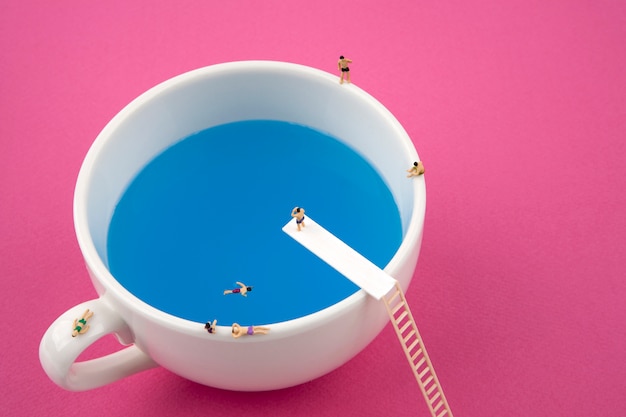 Gente en miniatura en taza taza piscina Foto Premium