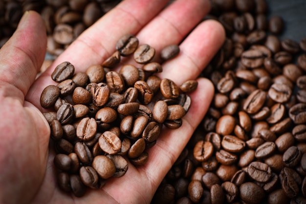 Granos de café en la mano y café tostado en grano. | Foto Premium