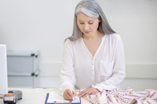 Grave Mujer Adulta De Pelo Largo Atento En Blusa Blanca Escribiendo