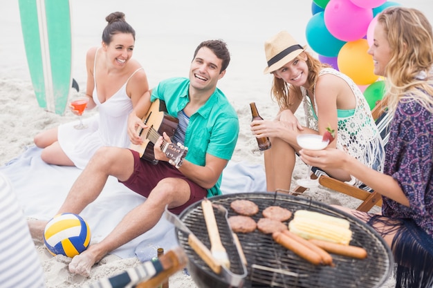 Grupo de amigos con bebidas y guitarra sentado junto a una ...