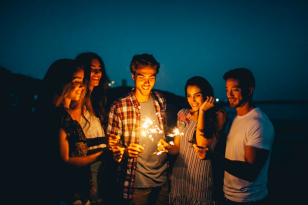 Grupo de amigos con bengala en una playa de noche Foto