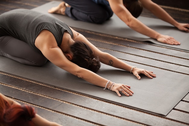 Grupo de jóvenes en pose balasana. Foto gratis