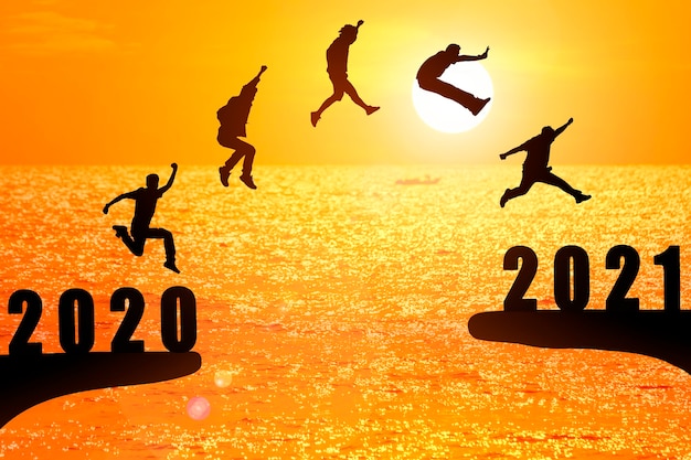 Grupo de silueta de jóvenes saltando entre 2020 y 2021 años con hermosa puesta de sol en el mar. Foto Premium 
