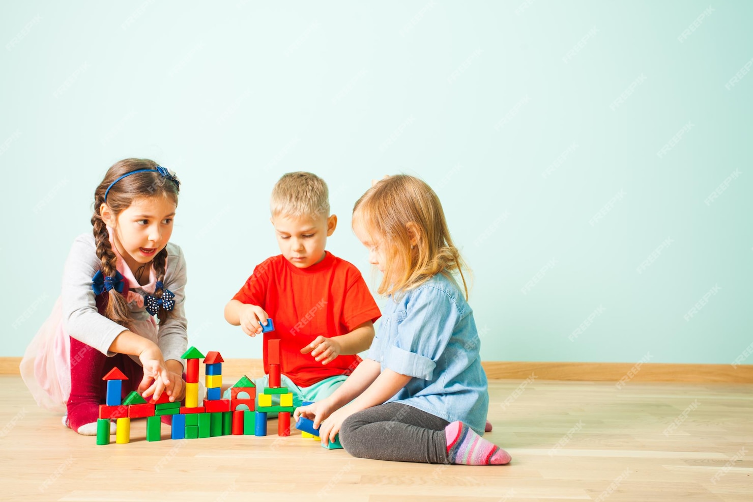 Grupo De Tres Niños Pequeños Sentados En Un Piso En El Preescolar Montessori Construyendo Torres 