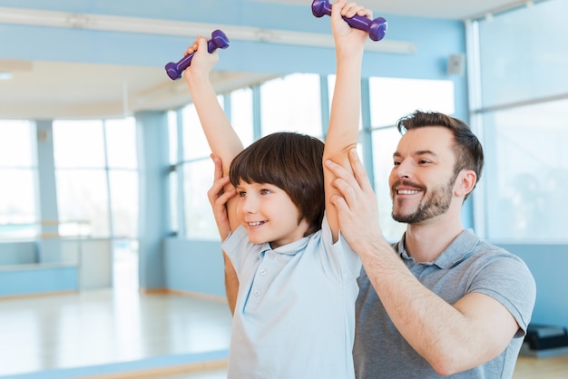 Hacer ejercicio con diversión feliz padre apoyando a su hijo en el