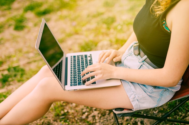 Hembra joven que trabaja en la computadora portátil en bosque Foto Gratis