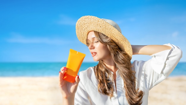 Hembra en sombrero de playa de paja con crema de protección solar spf ...