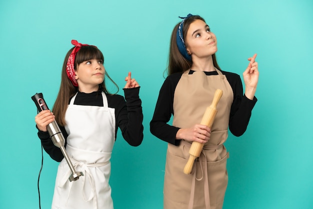 Hermanitas Cocinando En Casa Aislado Sobre Fondo Azul Con Los Dedos