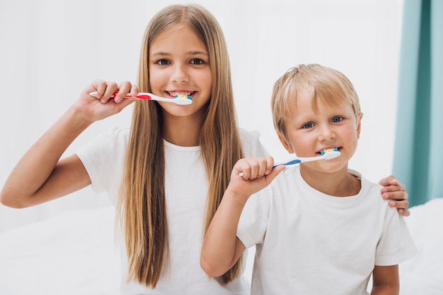 Hermanos cepillando sus dientes juntos Foto gratis