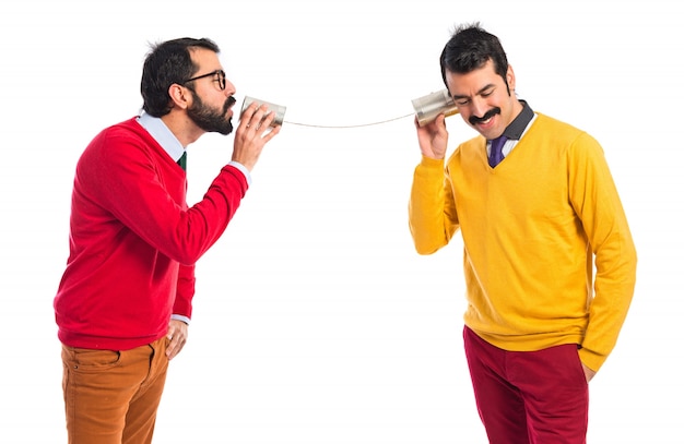 Hermanos gemelos hablando a través de un teléfono de hojalata Foto gratis