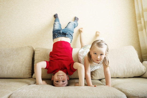 Hermanos y hermanas jugando en el sofá: el niño se pone de ...