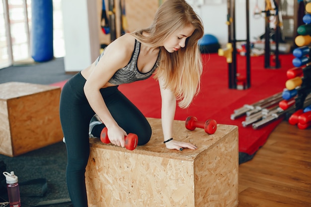 Una Hermosa Y Atlética Chica De Ropa Deportiva Se Encuentra En El Gimnasio Con Pesas Foto Gratis