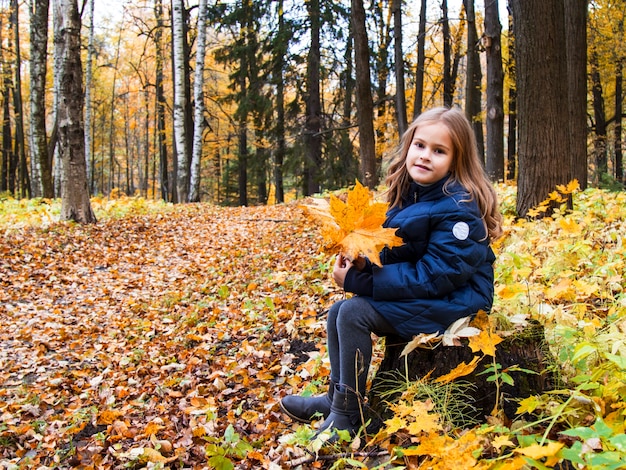 Hermosa chica con cabello largo y rubio en el parque de otoño chica de