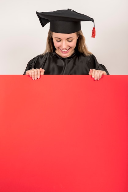 Hermosa graduada sosteniendo cartel rojo maqueta Foto gratis