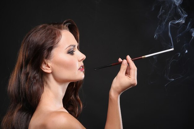 Hermosa Mujer Fumando Cigarro Sobre Fondo Oscuro Foto Premium