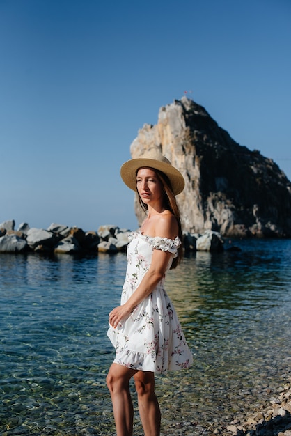 Una hermosa mujer joven con un sombrero y un vestido ligero está