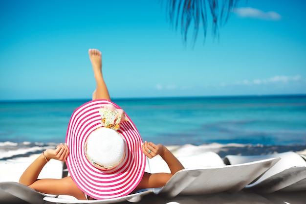 Hermosa Mujer Modelo Tomando El Sol En La Silla De Playa En Bikini Blanco En Colorido Sombrero