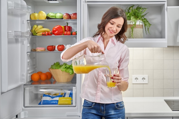 Hermosa mujer vertiendo jugo de naranja fresco en vidrio Foto Premium