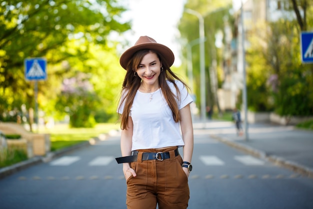 Una hermosa niña con un sombrero marrón y una camiseta blanca está