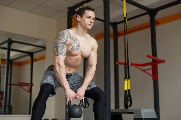 Hermoso Hombre Se Pone En Cuclillas Con Pesas Rusas En El Gimnasio