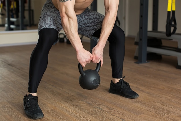 Hermoso Hombre Se Pone En Cuclillas Con Pesas Rusas En El Gimnasio