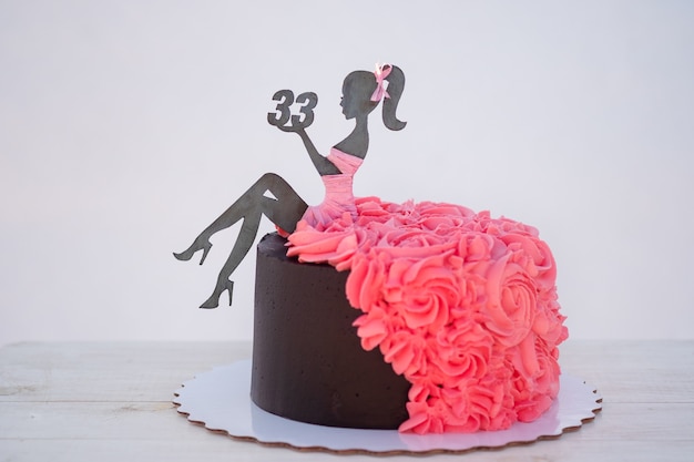 Hermoso Pastel De Cumpleanos Con La Figura De Una Mujer Y El Numero Treinta Y Tres Decorado Con Crema Rosa Foto Premium