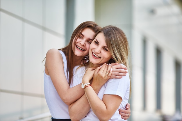 La hija adulta abraza a la madre y ambas están sonriendo a la cámara Foto Premium