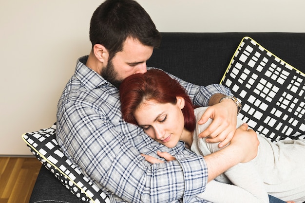 Hombre Abrazando A Su Esposa En El Sofá Foto Gratis