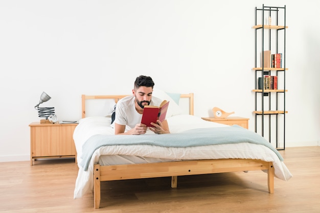 Hombre Acostado En La Cama Leyendo El Libro En El Dormitorio | Foto Gratis