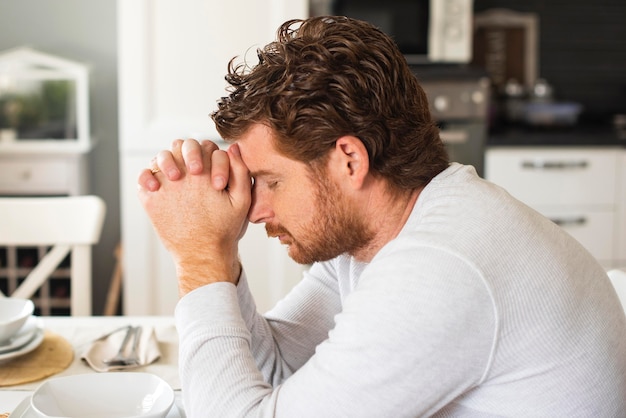 Hombre adulto emocional orando en casa Foto gratis