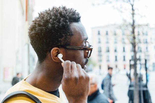 Hombre africano escuchando música a través de auriculares. él está poniendo el auricular es su oído. Foto Premium 