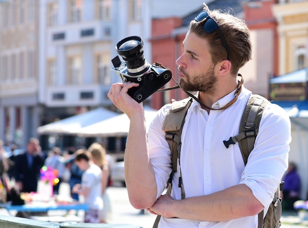 El hombre con barba tiene una cámara fotográfica en el fondo urbano el