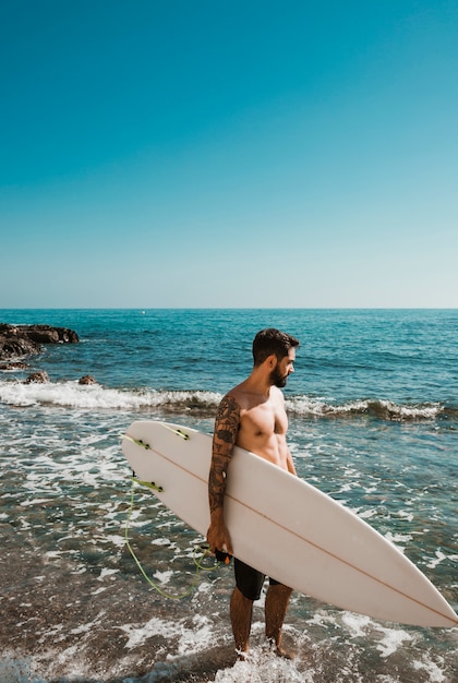 Hombre Barbudo Con Tabla De Surf Mirando Mar Agitando Foto Gratis